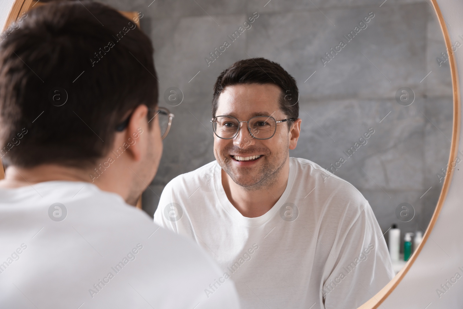 Handsome man looking at himself in mirror indoors Photo of Handsome man looking at himself in mirror indoors