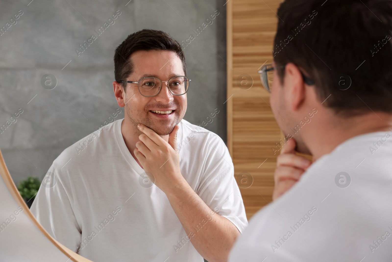 Handsome man looking at himself in mirror indoors Photo of Handsome man looking at himself in mirror indoors