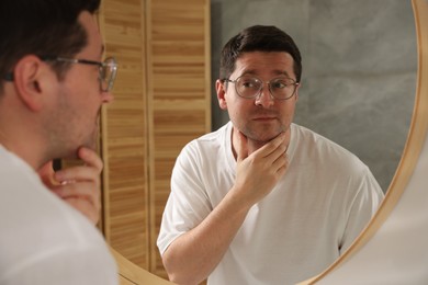 Photo of Handsome man looking at himself in mirror indoors