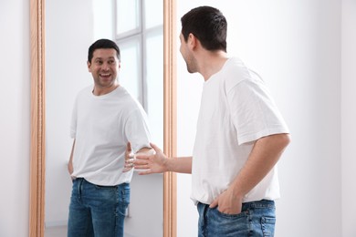 Photo of Handsome man looking at himself in mirror indoors