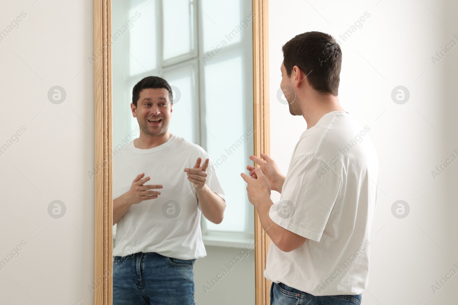 Handsome man looking at himself in mirror indoors Photo of Handsome man looking at himself in mirror indoors