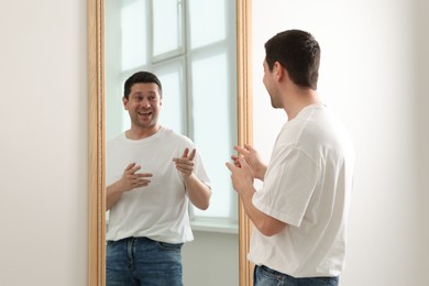 Photo of Handsome man looking at himself in mirror indoors