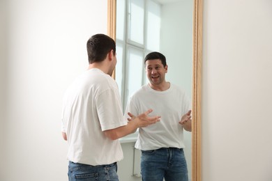 Photo of Handsome man looking at himself in mirror indoors