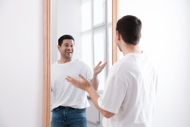 Photo of Handsome man looking at himself in mirror indoors