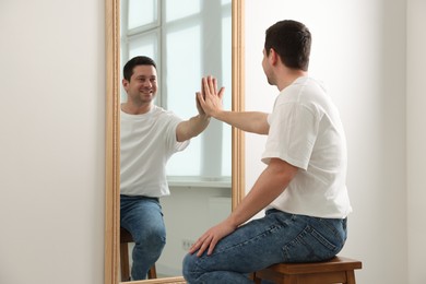 Photo of Handsome man looking at himself in mirror indoors