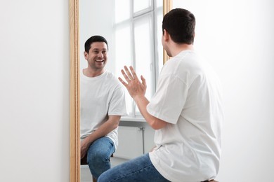 Photo of Handsome man looking at himself in mirror indoors