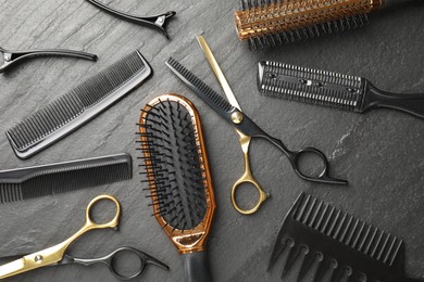 Photo of Different hairdresser's tools on dark table, flat lay