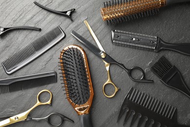 Photo of Different hairdresser's tools on dark table, flat lay