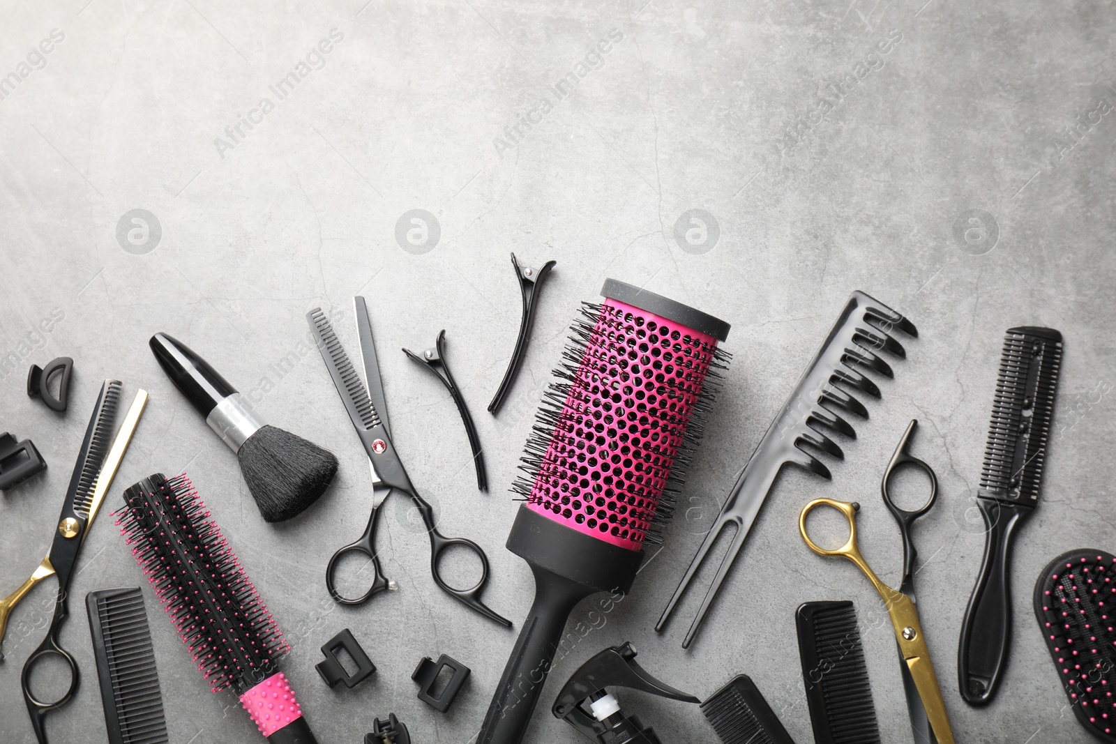 Different hairdresser's tools on grey table, flat lay. Space for text Photo of Different hairdresser's tools on grey table, flat lay. Space for text