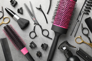 Photo of Different hairdresser's tools on grey table, flat lay