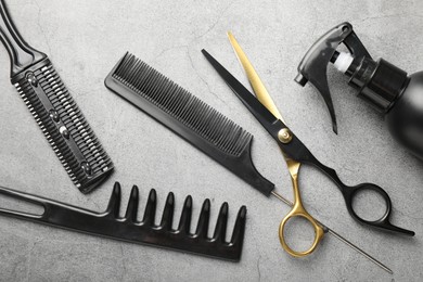 Photo of Different hairdresser's tools on grey table, flat lay