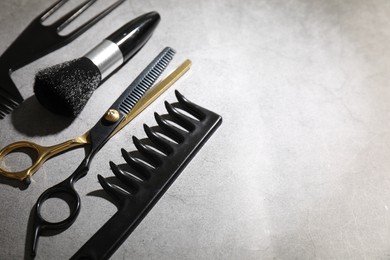 Photo of Different hairdresser's tools on grey table, closeup. Space for text