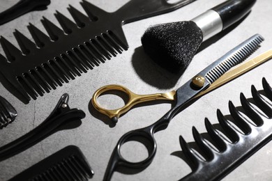Photo of Different hairdresser's tools on grey table, closeup