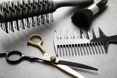 Photo of Different hairdresser's tools on grey table, closeup
