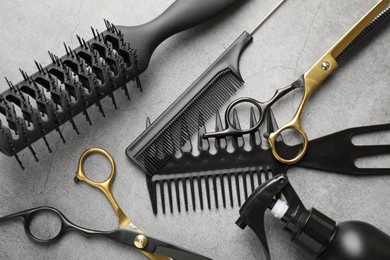 Photo of Different hairdresser's tools on grey table, flat lay