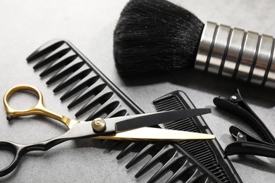 Photo of Different hairdresser's tools on grey table, closeup