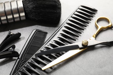 Photo of Different hairdresser's tools on grey table, closeup