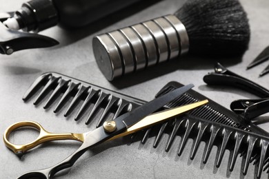 Photo of Different hairdresser's tools on grey table, closeup