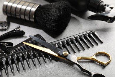 Photo of Different hairdresser's tools on grey table, closeup