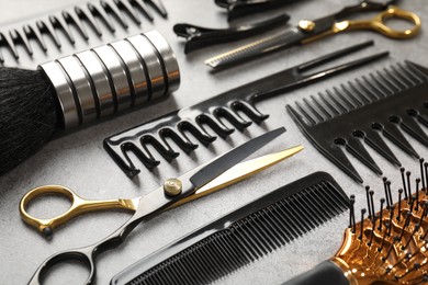 Photo of Different hairdresser's tools on grey table, closeup