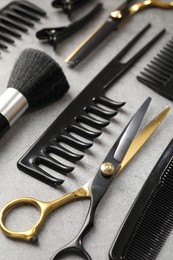 Photo of Different hairdresser's tools on grey table, closeup