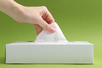 Photo of Woman taking handkerchief out of box on green background, closeup