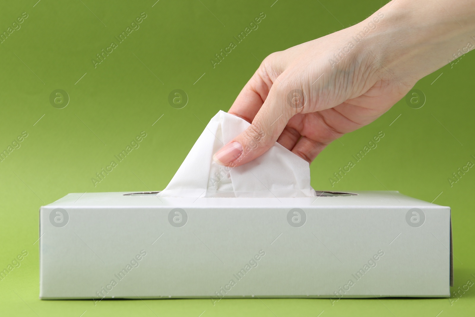 Woman taking handkerchief out of box on green background, closeup Photo of Woman taking handkerchief out of box on green background, closeup