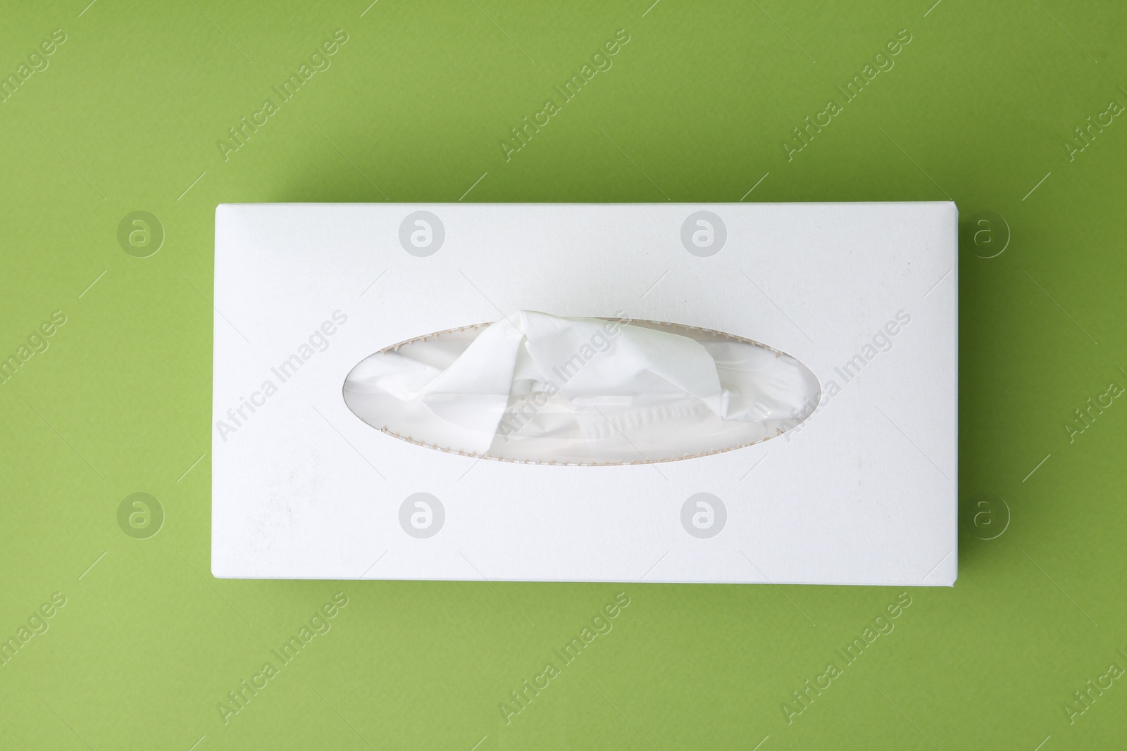 Box with paper handkerchiefs on green background, top view Photo of Box with paper handkerchiefs on green background, top view