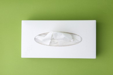Photo of Box with paper handkerchiefs on green background, top view