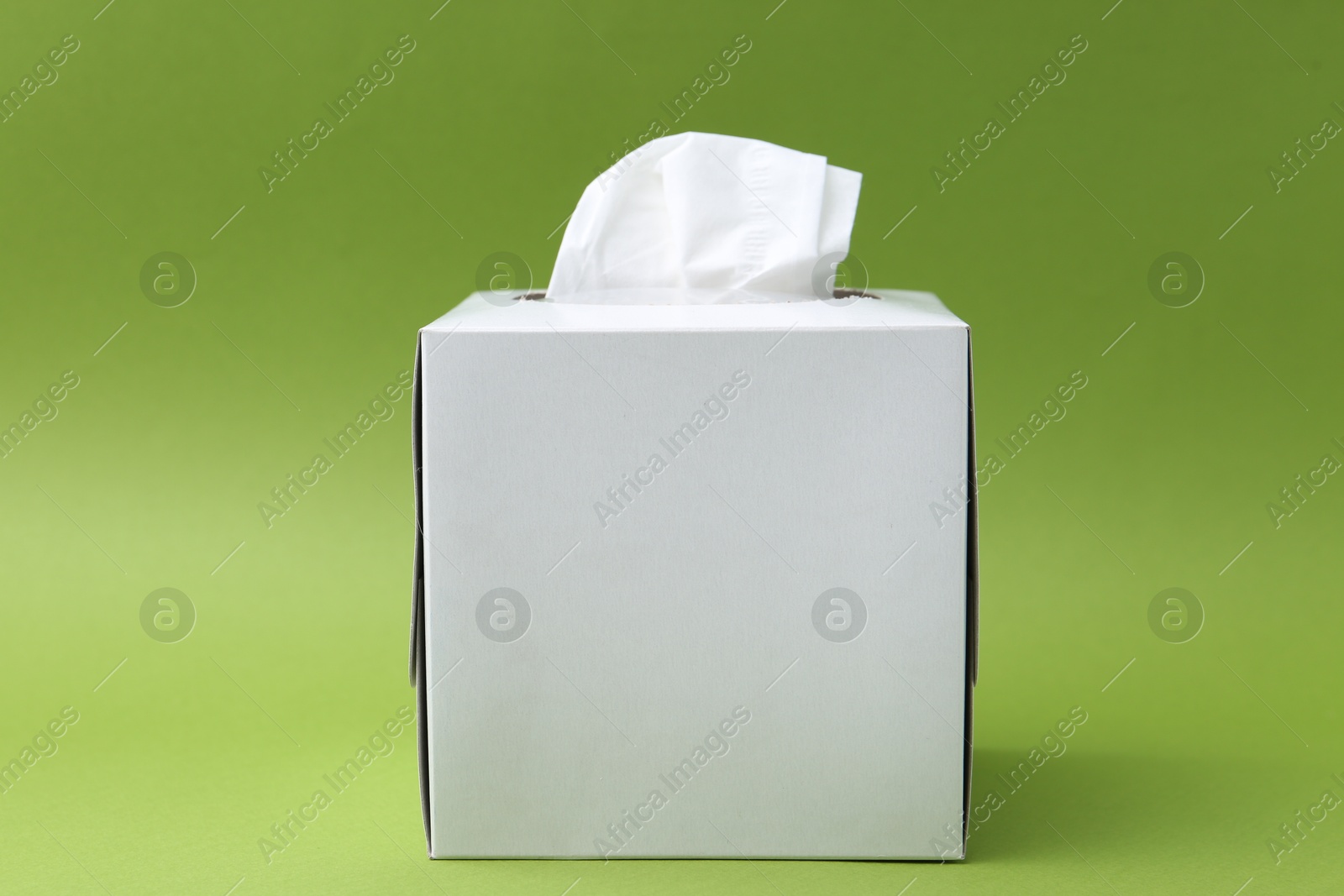 Box with paper handkerchiefs on green background Photo of Box with paper handkerchiefs on green background