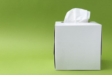 Photo of Box with paper handkerchiefs on green background. Space for text