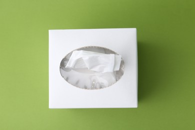 Photo of Box with paper handkerchiefs on green background, top view