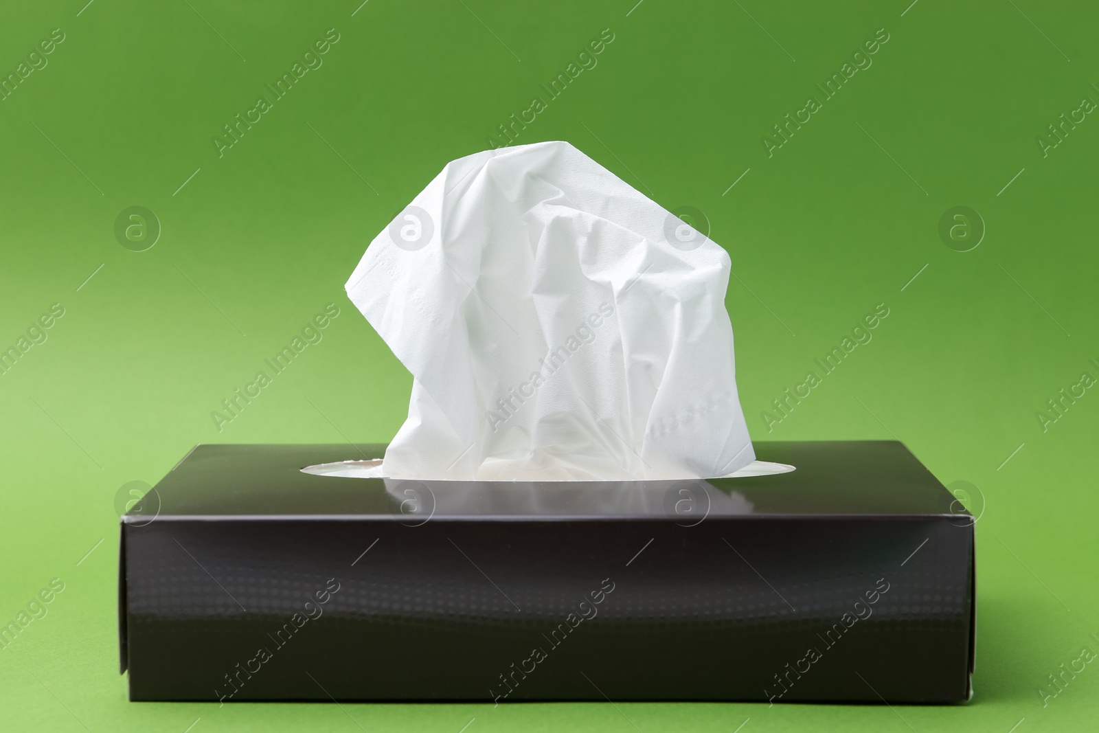 Box with paper handkerchiefs on green background Photo of Box with paper handkerchiefs on green background