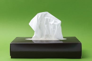 Photo of Box with paper handkerchiefs on green background