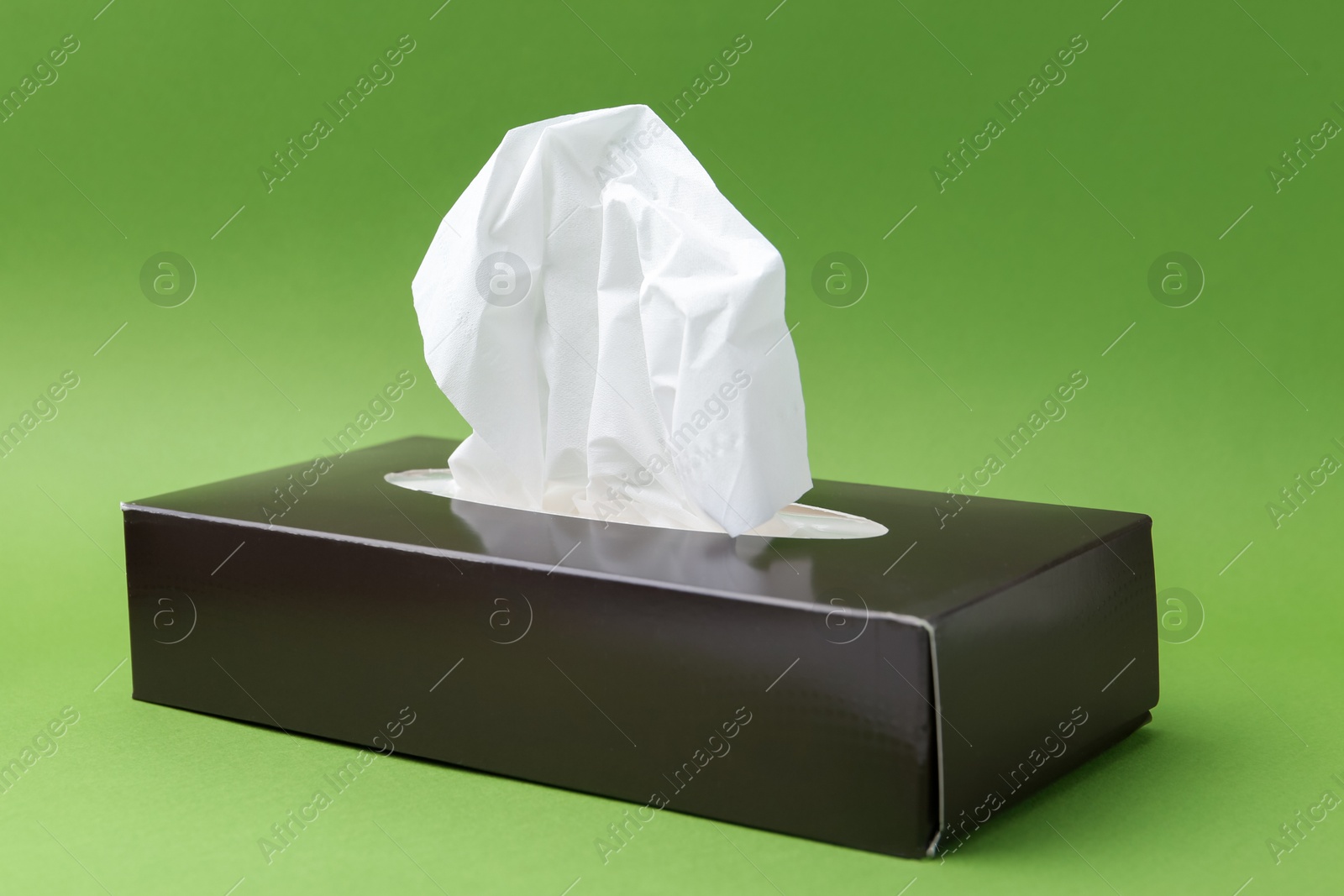 Box with paper handkerchiefs on green background Photo of Box with paper handkerchiefs on green background