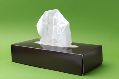 Photo of Box with paper handkerchiefs on green background