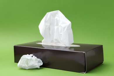 Photo of Box with paper handkerchiefs on green background
