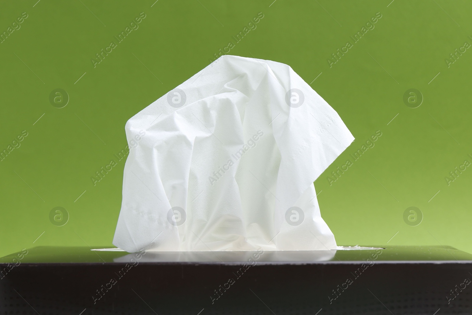 Box with paper handkerchiefs on green background, closeup Photo of Box with paper handkerchiefs on green background, closeup