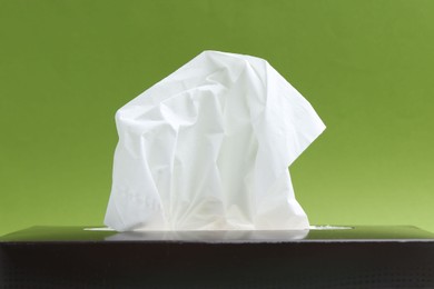Photo of Box with paper handkerchiefs on green background, closeup