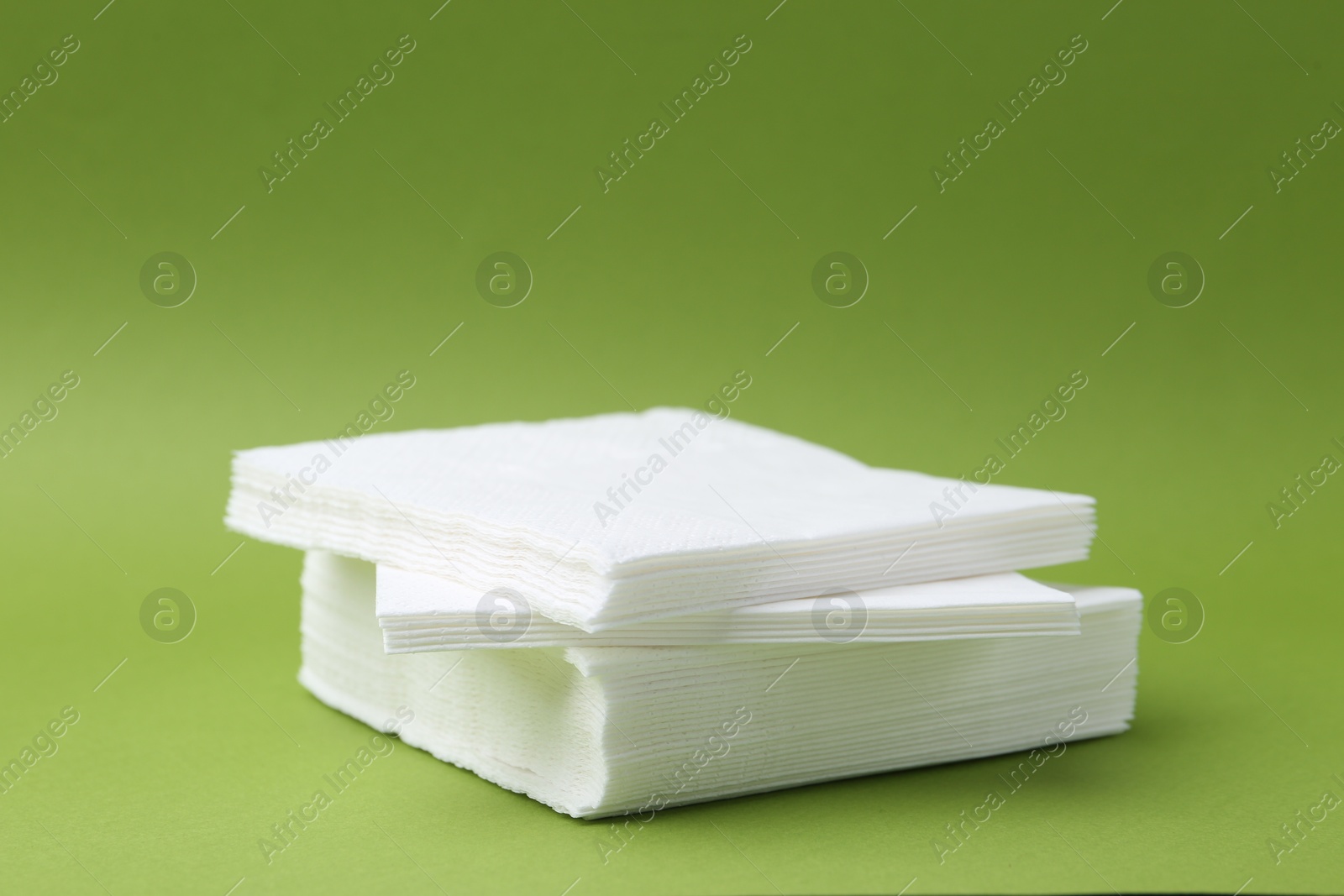 Stack of white handkerchiefs on green background, closeup. Space for text Photo of Stack of white handkerchiefs on green background, closeup. Space for text