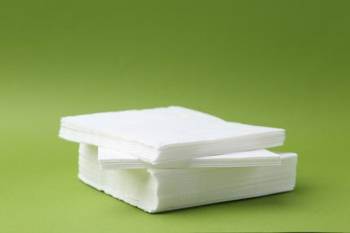 Photo of Stack of white handkerchiefs on green background, closeup. Space for text