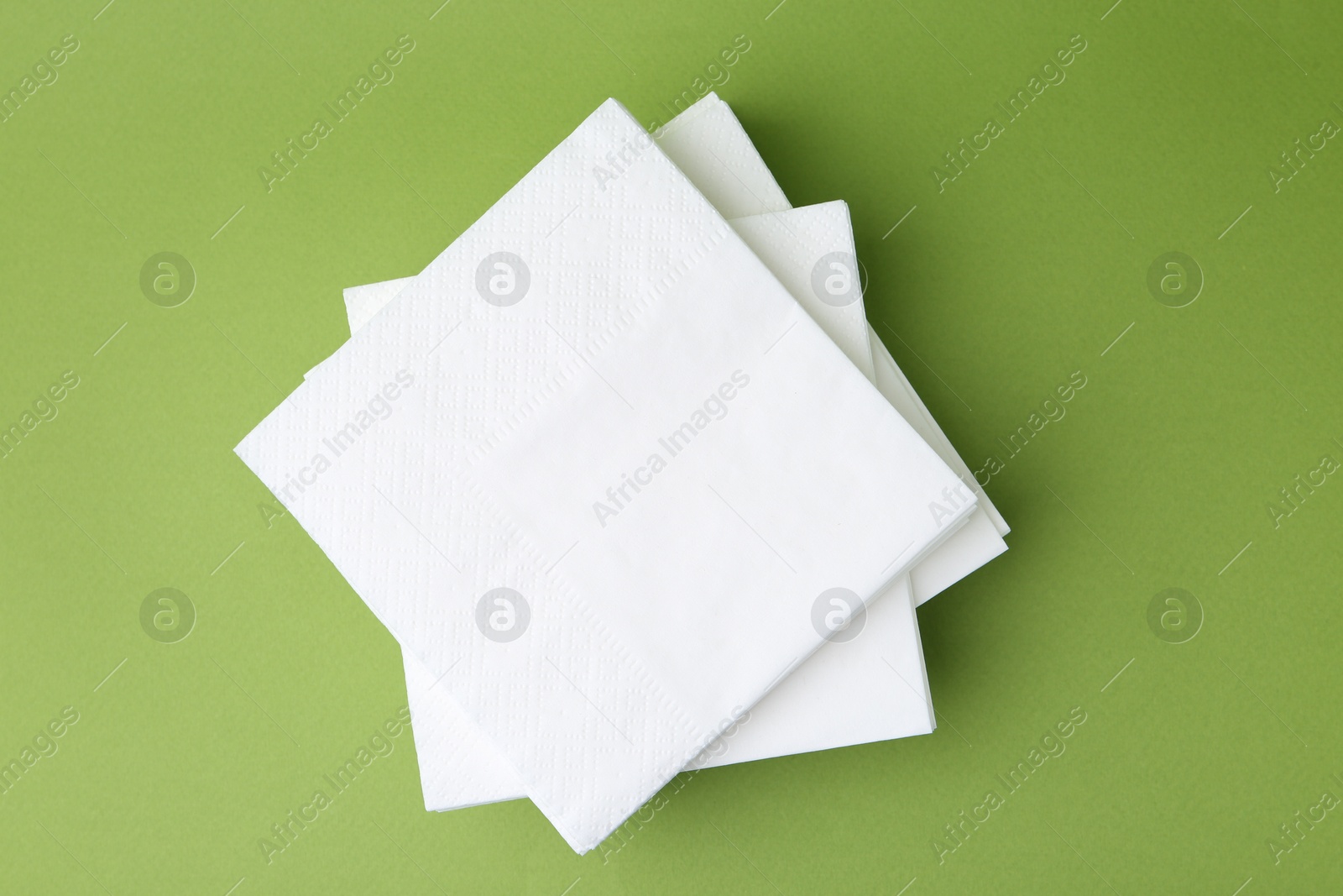 Stack of white handkerchiefs on green background, top view Photo of Stack of white handkerchiefs on green background, top view