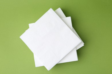 Photo of Stack of white handkerchiefs on green background, top view