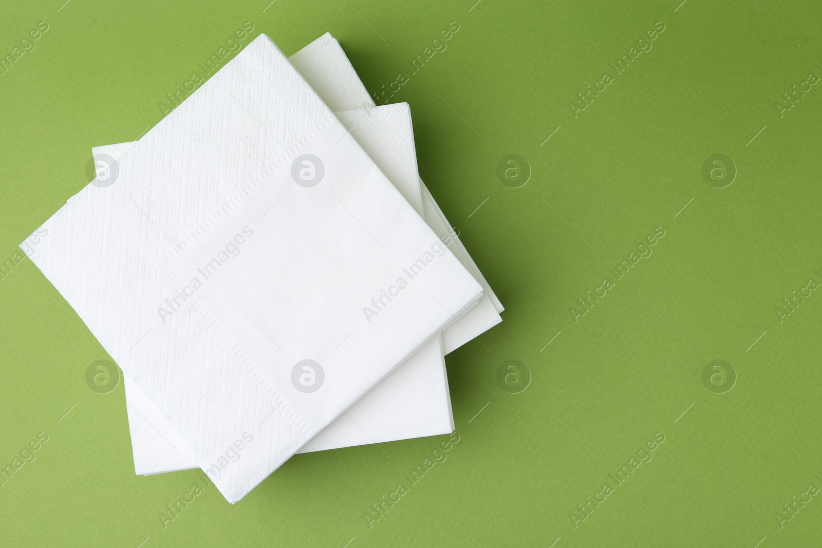 Stack of white handkerchiefs on green background, top view. Space for text Photo of Stack of white handkerchiefs on green background, top view. Space for text