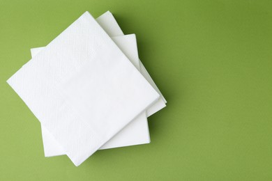Photo of Stack of white handkerchiefs on green background, top view. Space for text
