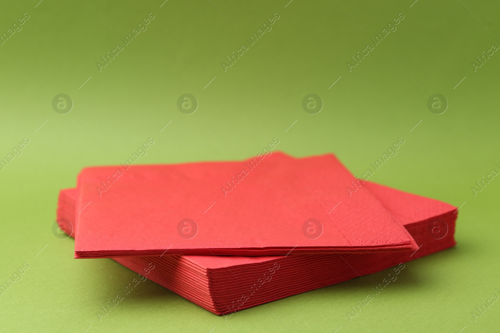 Stack of red handkerchiefs on green background, closeup. Space for text Photo of Stack of red handkerchiefs on green background, closeup. Space for text