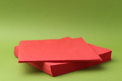Photo of Stack of red handkerchiefs on green background, closeup. Space for text