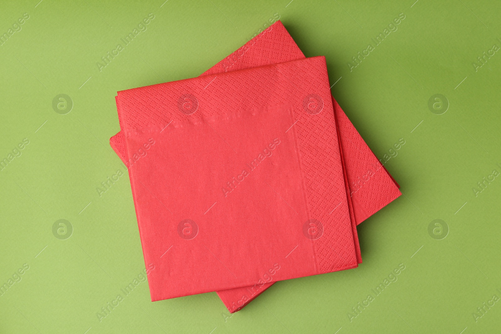 Stack of red handkerchiefs on green background, top view Photo of Stack of red handkerchiefs on green background, top view