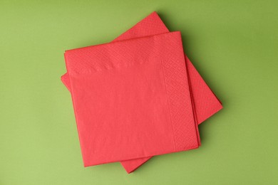 Photo of Stack of red handkerchiefs on green background, top view