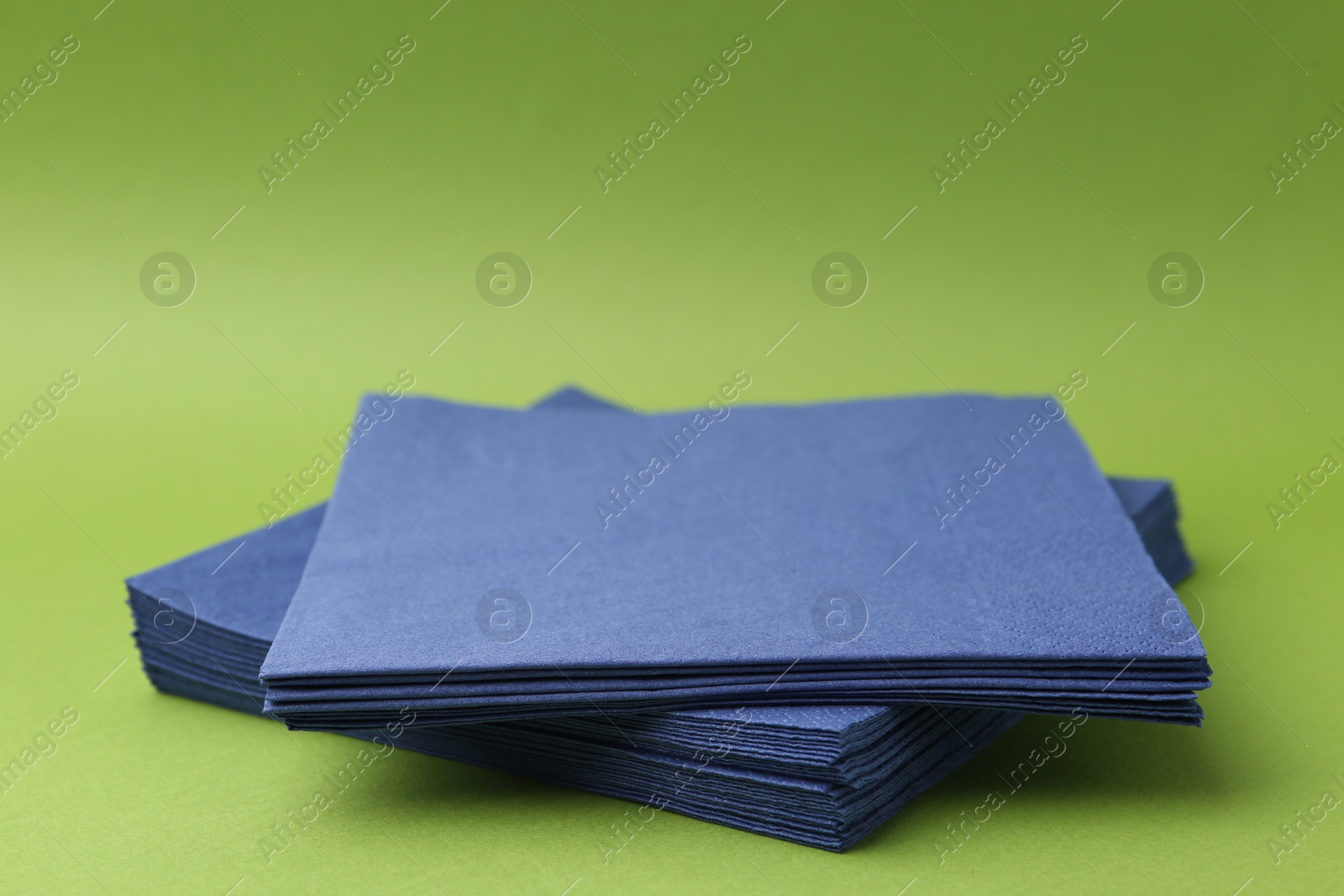 Stack of blue handkerchiefs on green background, closeup. Space for text Photo of Stack of blue handkerchiefs on green background, closeup. Space for text